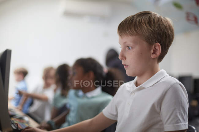 Écolier utilisant l'ordinateur en classe à l'école primaire — Photo de stock