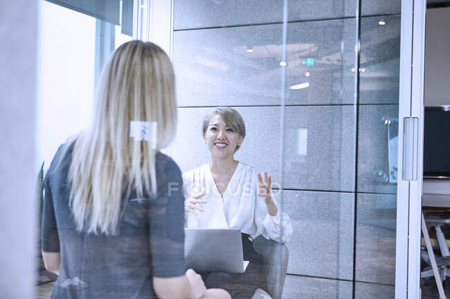 View through glass wall of colleagues having meeting in office — Stock Photo