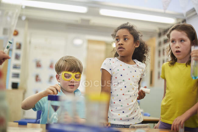 Primary schoolgirls and boys doing experiments in classroom — Stock Photo