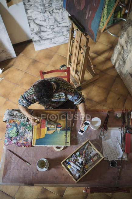Artista che guarda smartphone mentre dipinge su tela in studio — Foto stock