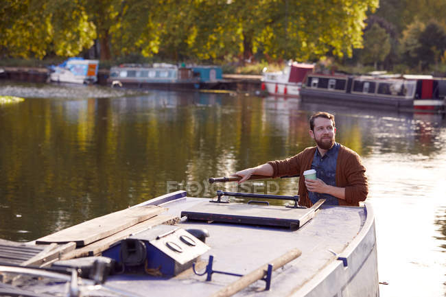 Man with coffee cup on canal boat — Stock Photo