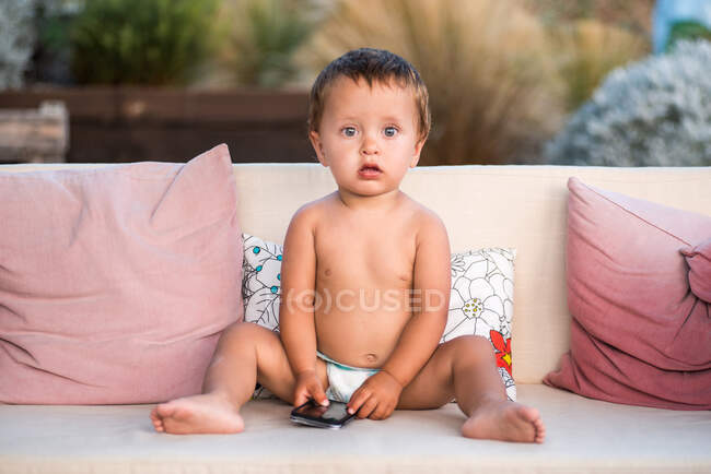 Baby boy holding smartphone looking at camera — Stock Photo