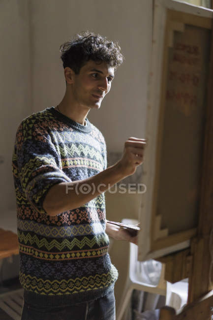 Мужская живопись на мольберте в мастерской художника — стоковое фото