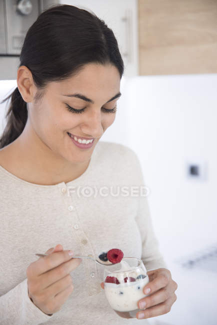 Закрыть женщину, которая ест фрукты и йогурт — стоковое фото