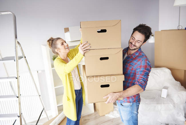 Jovem casal em nova casa com pilha de caixas de papelão — Fotografia de Stock