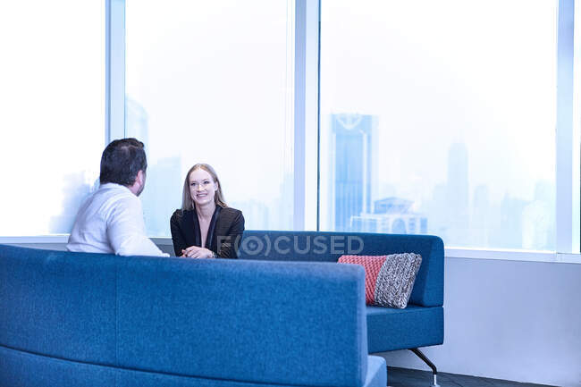 Колеги в офісі на диванах спілкуються — стокове фото