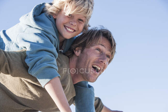 Padre che porta un ragazzo sorridente sul retro — Foto stock