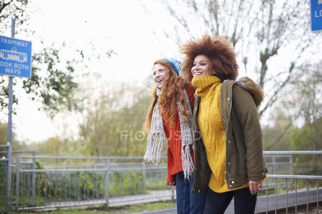Amigos en la estación de tren mirando hacia otro lado y sonriendo - foto de stock