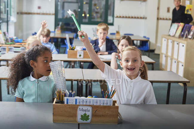 Schulmädchen mit erhobener Hand im Grundschulunterricht — Stockfoto