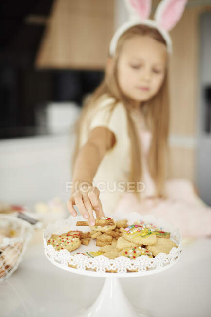 Ragazza selezionando da biscotti pasquali sul bancone della cucina — Foto stock