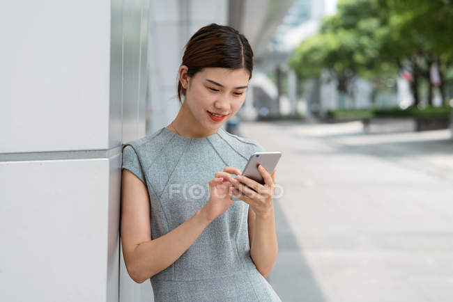 Jeune femme d'affaires utilisant un smartphone dans la ville, Shanghai, Chine — Photo de stock