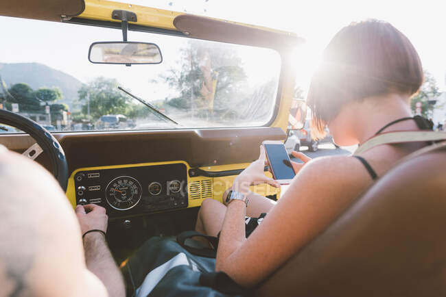 Junge Frau schaut im Geländewagen aufs Smartphone, Como, Lombardei, Italien — Stockfoto