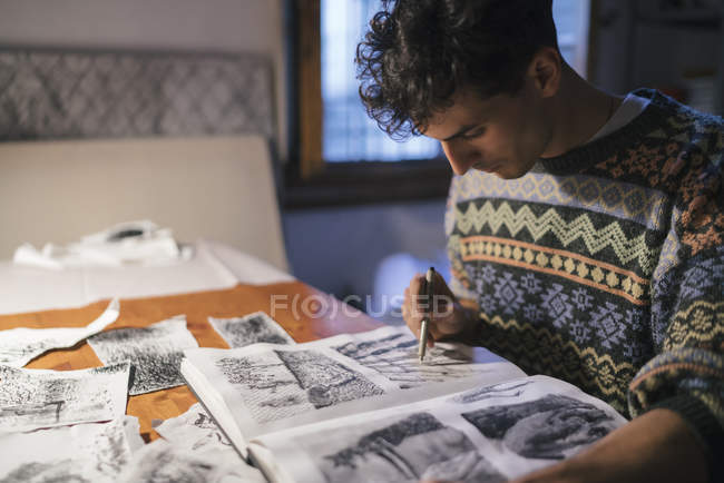 Jovem artista desenhando em caderno de esboços na mesa em estúdio — Fotografia de Stock