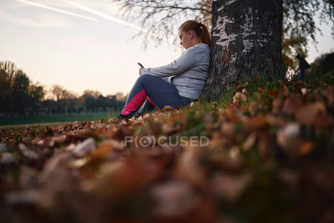 Молодая женщина обучение и взятие со смартфона в парке — стоковое фото