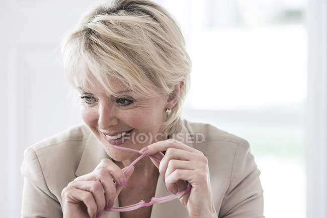 Portrait de femme d'affaires tenant des lunettes de lecture détournant les yeux souriant — Photo de stock