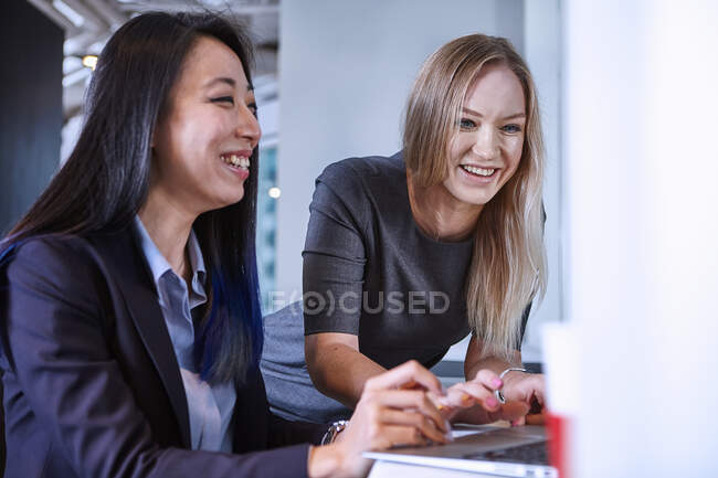 Colleagues using laptop smiling — Stock Photo