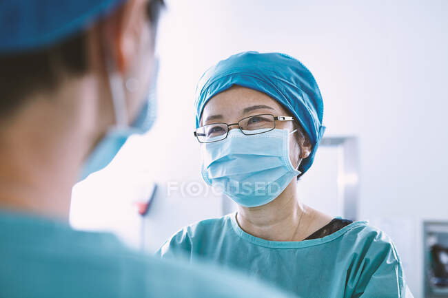 Sobre a visão do ombro da equipe cirúrgica vestindo esfoliação tendo discussão na maternidade sala de operações — Fotografia de Stock