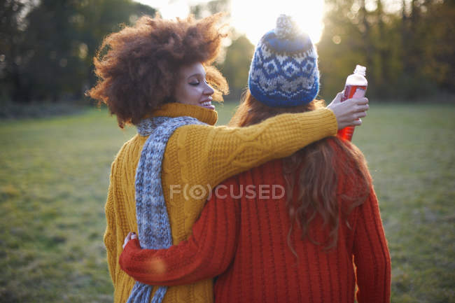 Dos mujeres jóvenes caminando con los brazos alrededor de la otra - foto de stock