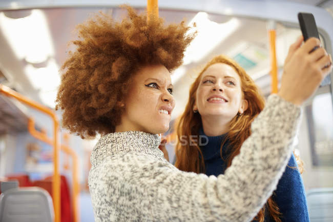 Friends taking selfie with mobile phone on train — Stock Photo