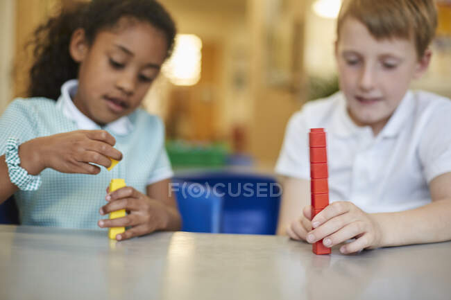 Écolier et fille empilant des blocs de jouets dans la salle de classe à l'école primaire — Photo de stock