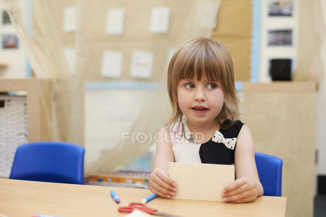 Primary schoolgirl looking sideways from classroom desk — Stock Photo