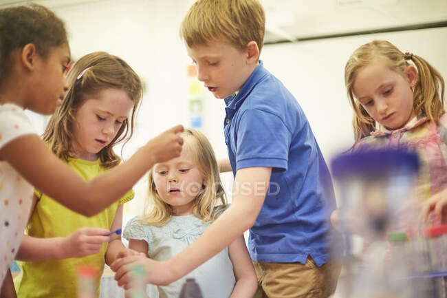 Primary schoolboy and girls doing teamwork project in classroom — Stock Photo