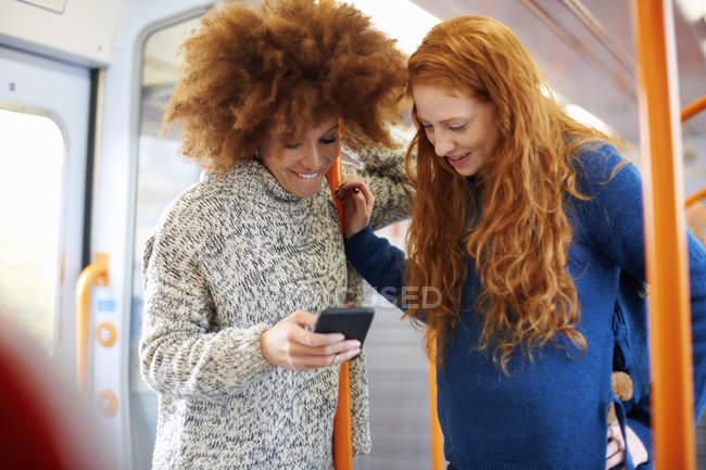 Friends looking at on mobile phone in train — Stock Photo