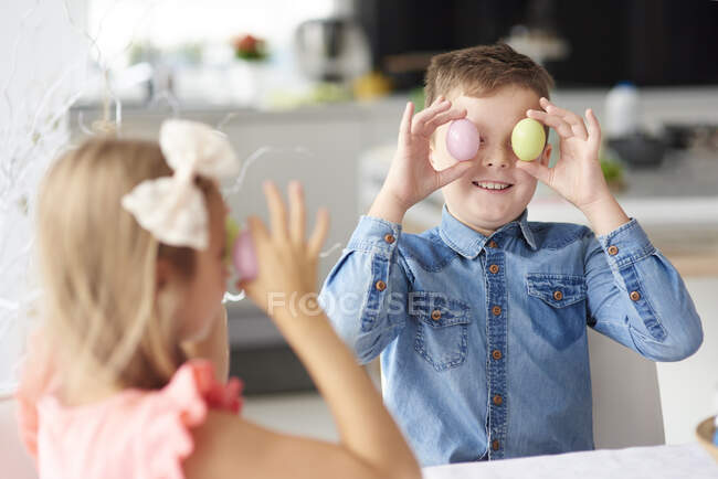 Девушка с братом держат пасхальные яйца над глазами — стоковое фото