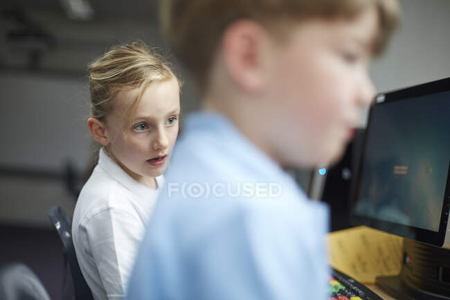 Colegiala y niño usando computadoras en el aula en la escuela primaria - foto de stock