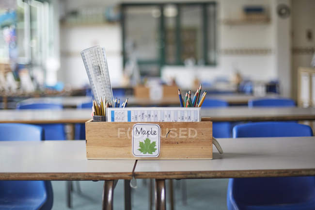 Klassenzimmertisch mit Holzkiste voller Bleistifte und Lineale im Klassenzimmer der Grundschule — Stockfoto