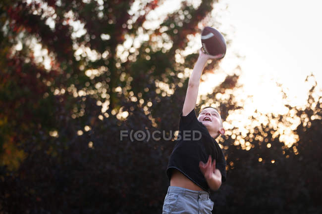 Rapaz praticando futebol americano no jardim — Fotografia de Stock