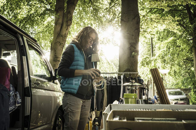 Female stall holder unpacking second hand lamp on stall at forest flea market — Stock Photo