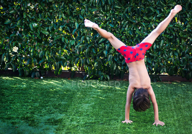 Мальчик делает стойку на руках на траве — стоковое фото