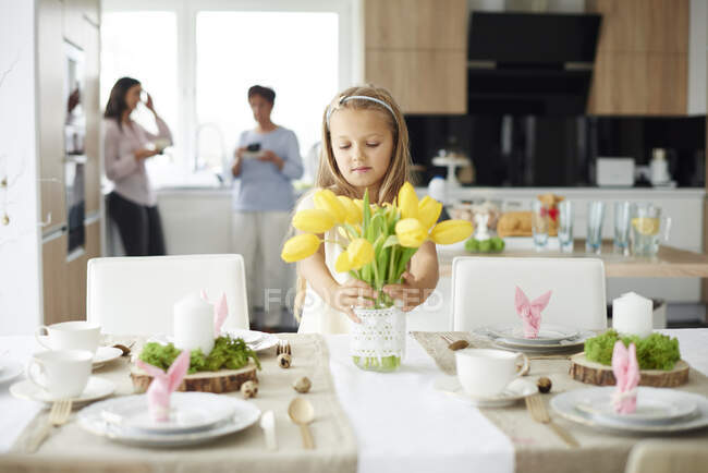 Menina organizando tulipas amarelas na mesa de jantar de Páscoa — Fotografia de Stock