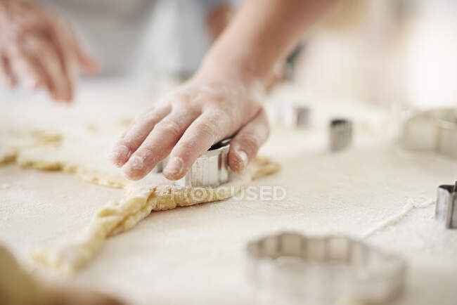 Mani di ragazza e nonna che tagliano biscotti pasquali al bancone della cucina — Foto stock