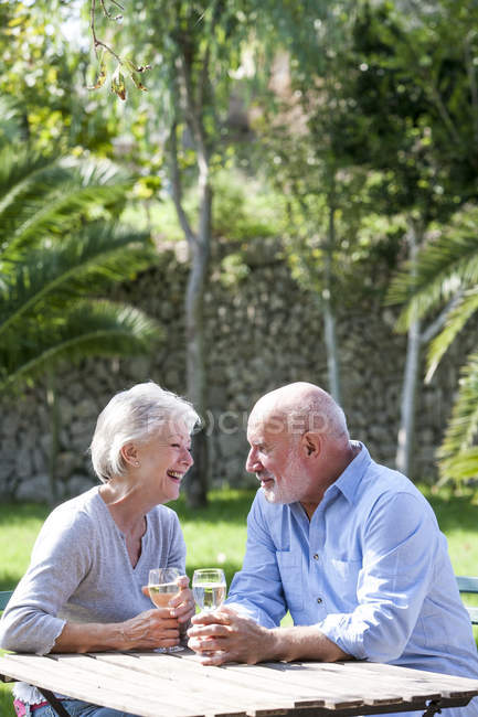 Coppia anziana seduta in giardino, gustando un bicchiere di vino — Foto stock