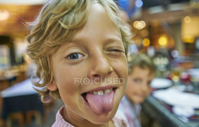 Retrato del niño mirando a la cámara, sacando la lengua - foto de stock