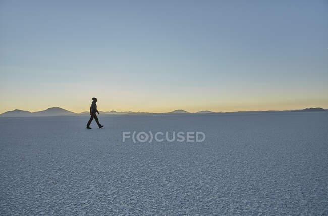 Woman walking across salt flats, Salar de Uyuni, Uyuni, Oruro, Bolivia, South America — Stock Photo