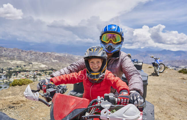 Madre e hijo en la cima de la montaña, usando quad bike, La Paz, Bolivia, América del Sur - foto de stock