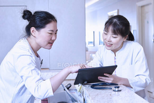 Медичні працівники на стійці реєстрації в лікарні використовують цифровий планшет — стокове фото