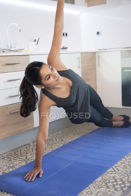 Mulher formação em casa no tapete de ioga — Fotografia de Stock