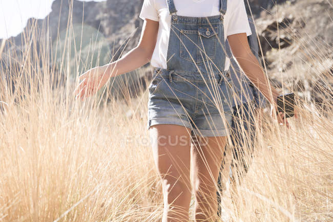 Средняя часть молодой пары пеших походов касающихся длинной травы во время похода в долине Лас-Пальмас, Канарские острова, Испания — стоковое фото