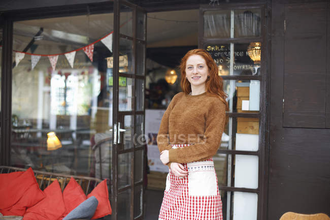 Portrait of small business owner in front of cafe smiling at camera — Stock Photo