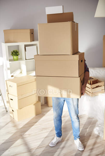 Moving home, young man holding stack of cardboard boxes — Stock Photo