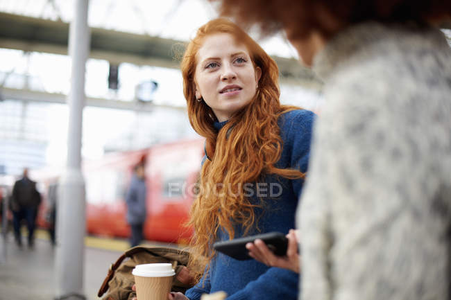 Amici che parlano in panchina alla stazione ferroviaria — Foto stock
