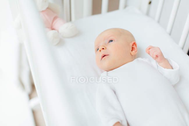Elevated view of of baby girl lying in crib — Stock Photo