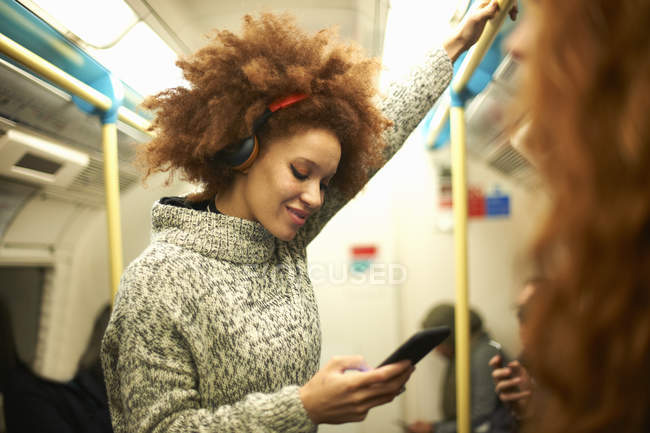 Молода жінка на поїзді метро дивиться на смартфон — стокове фото