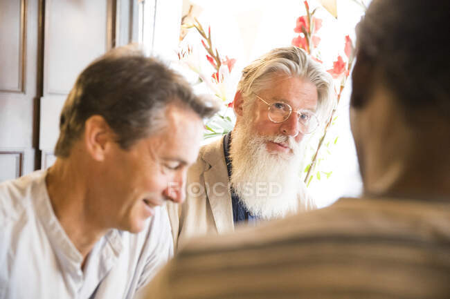Three mature men, standing together in pub — Stock Photo