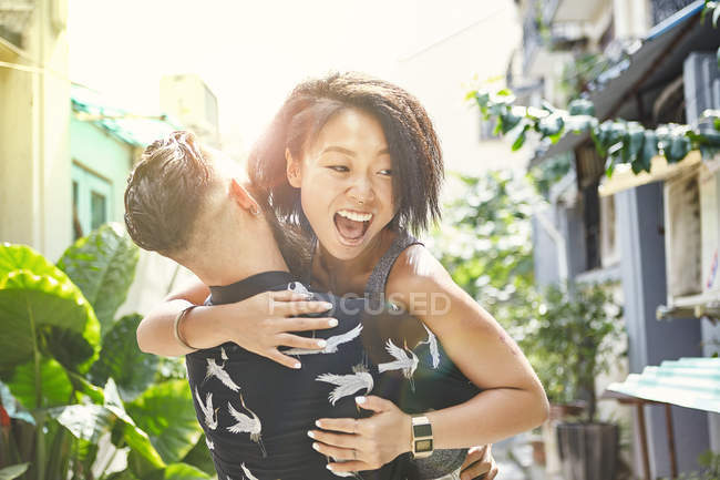Jovem homem levantando e abraçando namorada no beco residencial, Shanghai French Concession, Shanghai, China — Fotografia de Stock