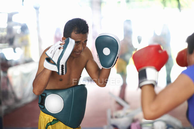 Зрелая женщина занимается боксом с тренером-мужчиной в спортзале — стоковое фото